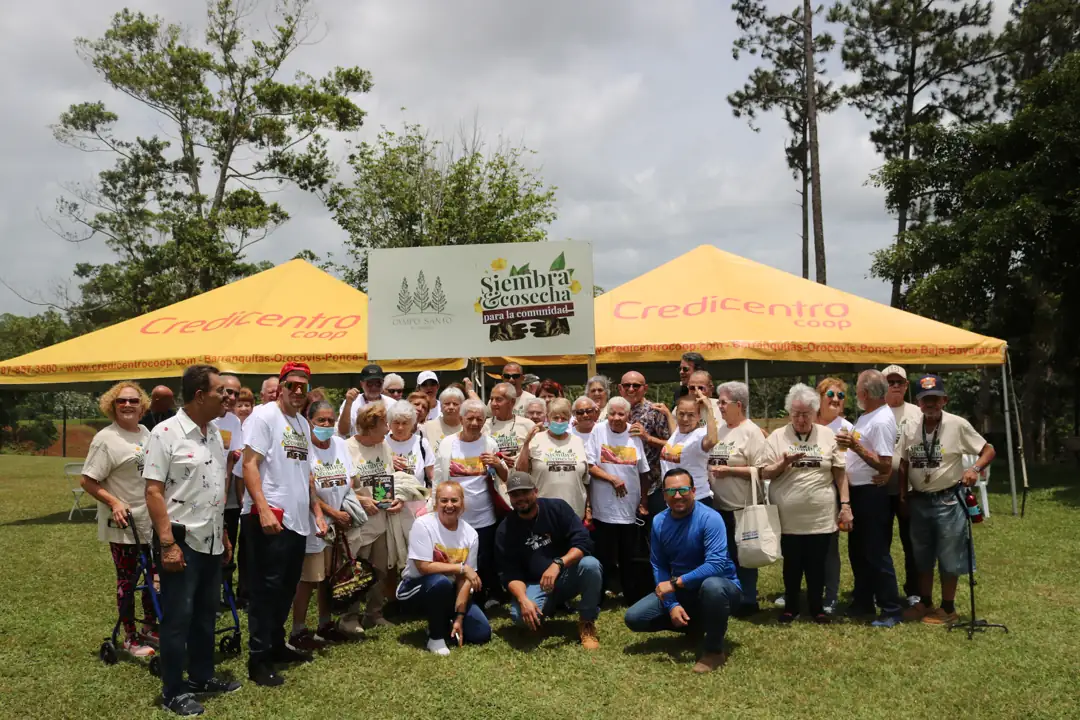La comunidad reunida frente al rótulo de Siembra y Cosecha durante un encuentro anterior.